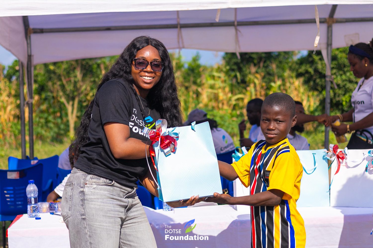 A volunteer presenting a gift bag to a child